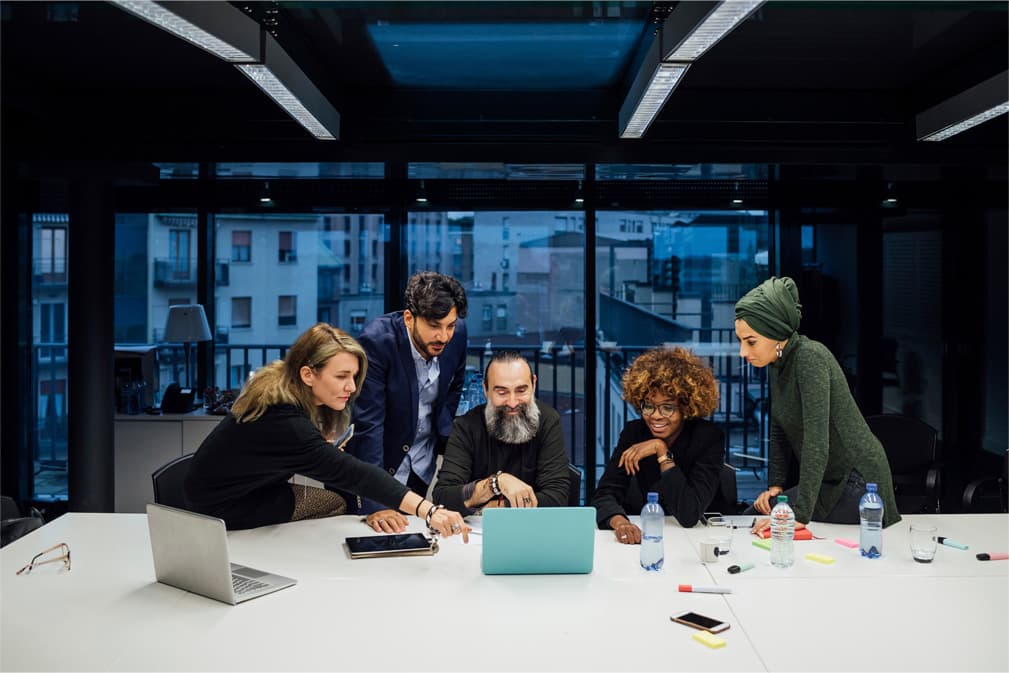 Group of diverse professionals sitting in office chairs with one woman smiling in front