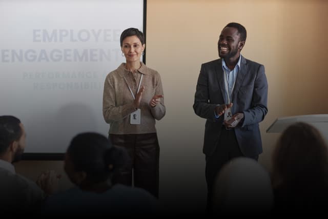 Human Resource Training: Two professionals standing and smiling in office environment