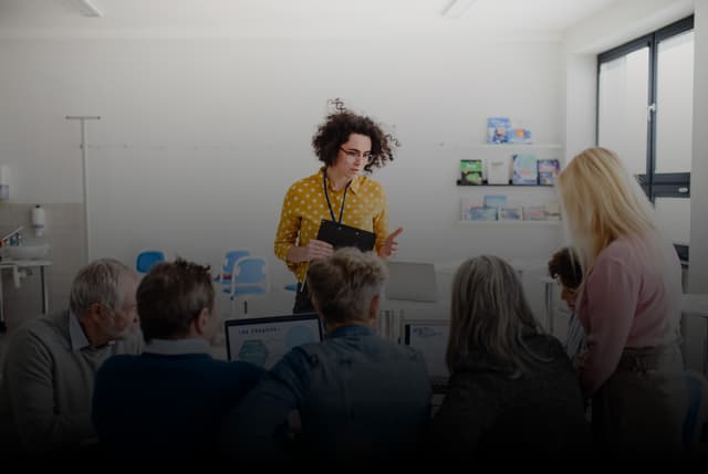Business Executive Training: Woman in yellow shirt presenting to a group in a meeting room