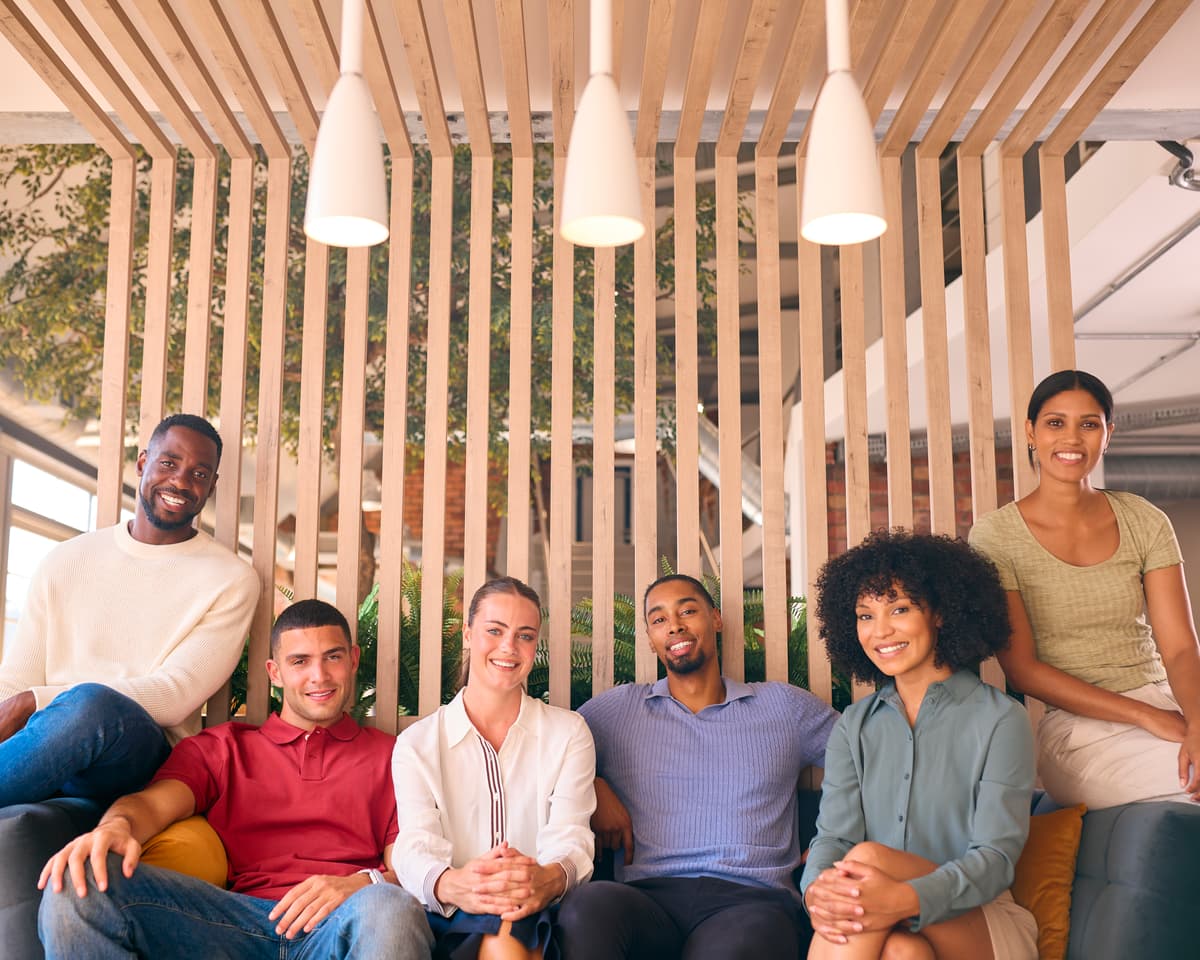 Group of diverse professionals sitting in office chairs with one woman smiling in front