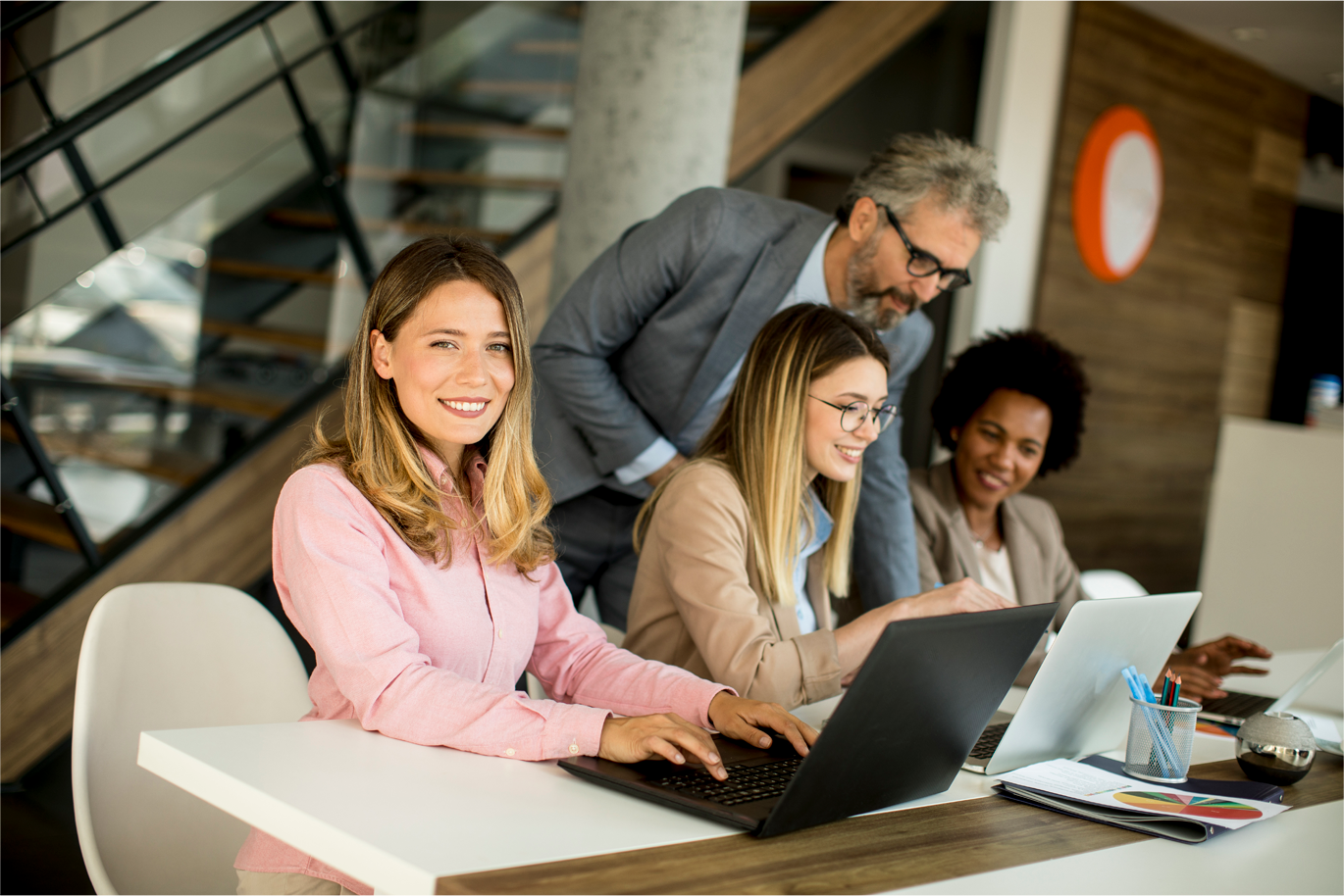 Group of diverse professionals sitting in office chairs with one woman smiling in front